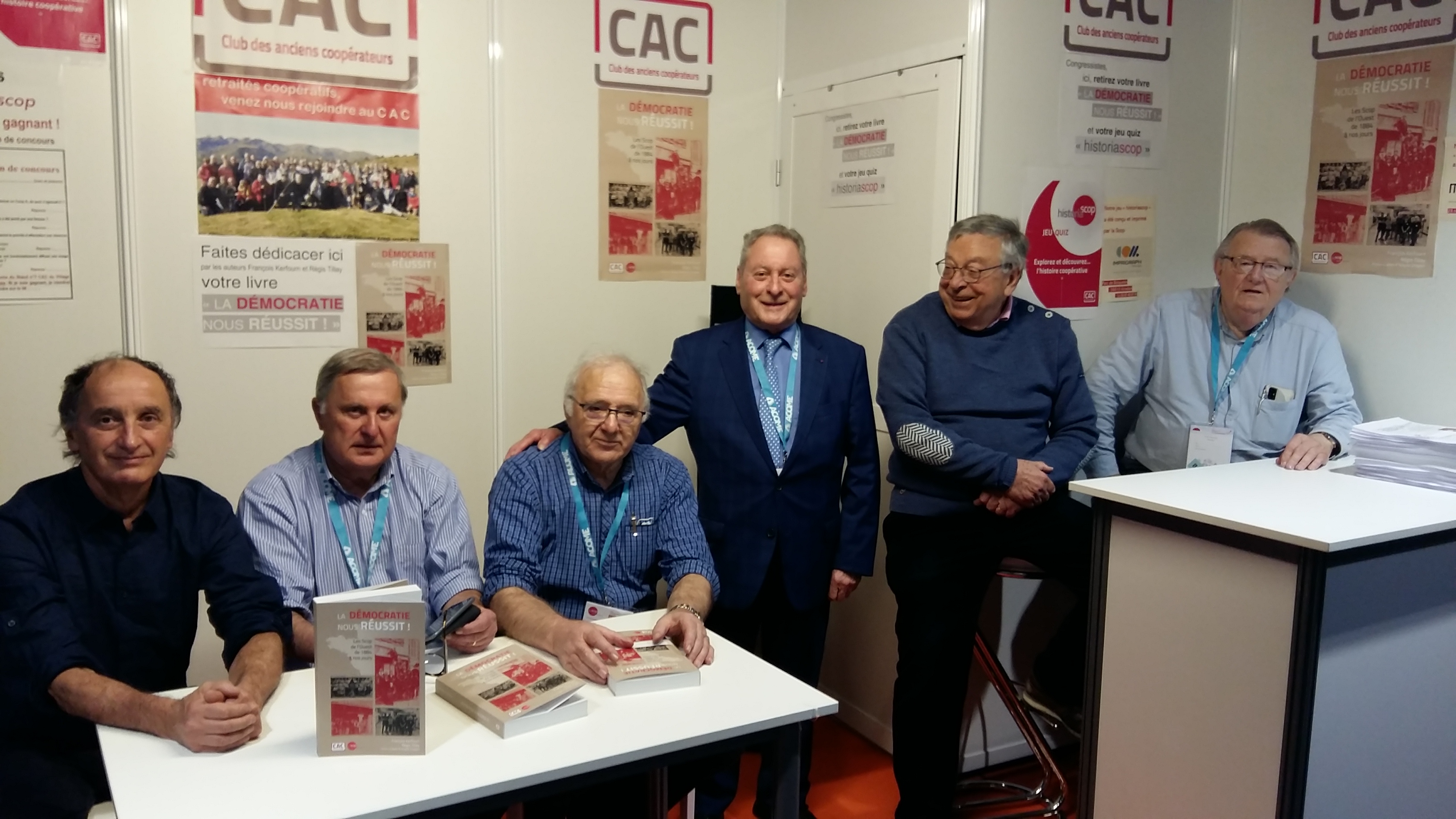 Photo prise le 16 mars, la veille du Congrès, après l’installation du stand CAC. De gauche à droite : Jean-François Draperi, préfacier du livre, Régis Tillay et François Kerfourn, rédacteurs du livre La démocratie nous réussit, Jean-Marie Courtois, ancien président de la CG Scop, venu saluer les membres du CAC, Michel Porta, coordinateur de la rédaction du quizz Historiascop et Jean-Jacques Brunellière président du Club des Anciens Coopérateurs.